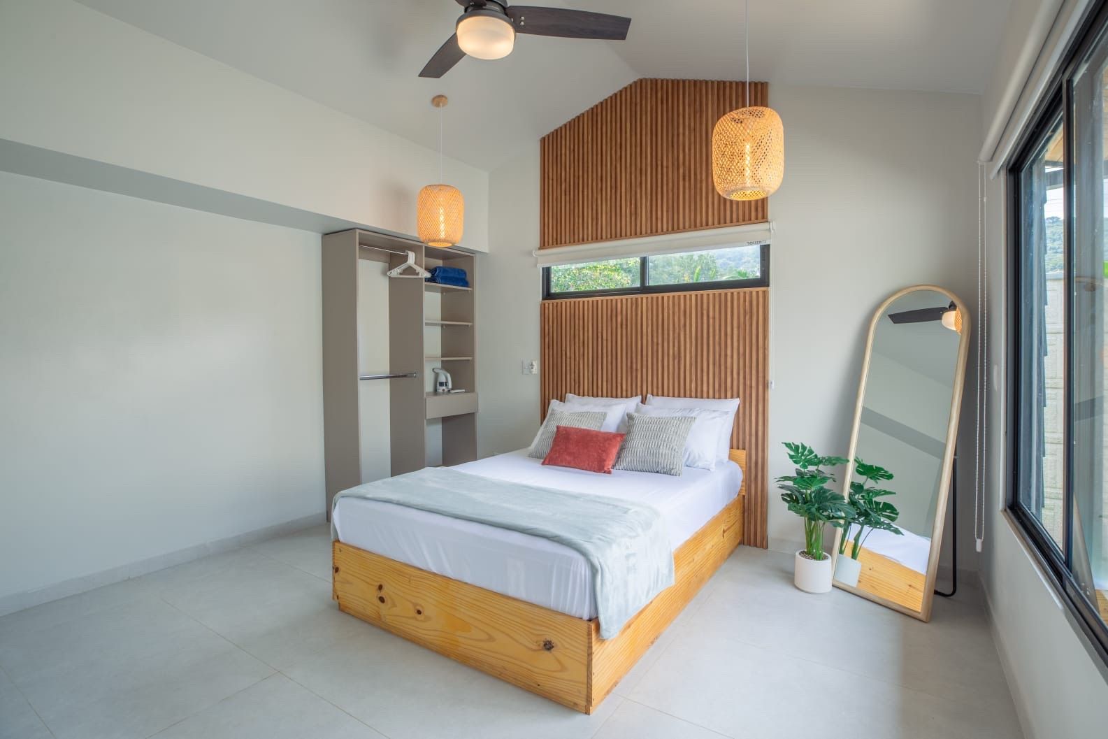Bedroom with a double bed, open wardrobe shelving, ceiling fan and large windows