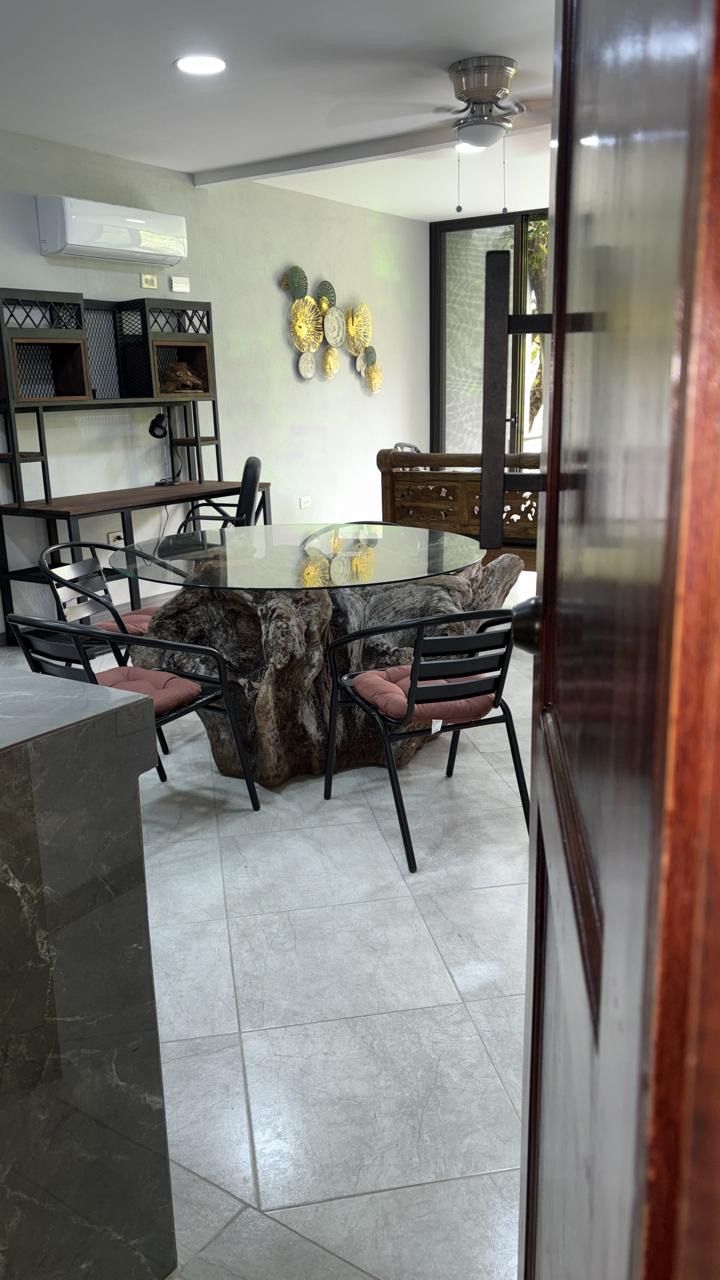 Dining area with a glass-top driftwood table, four chairs, a desk, wall A/C and ceiling fan